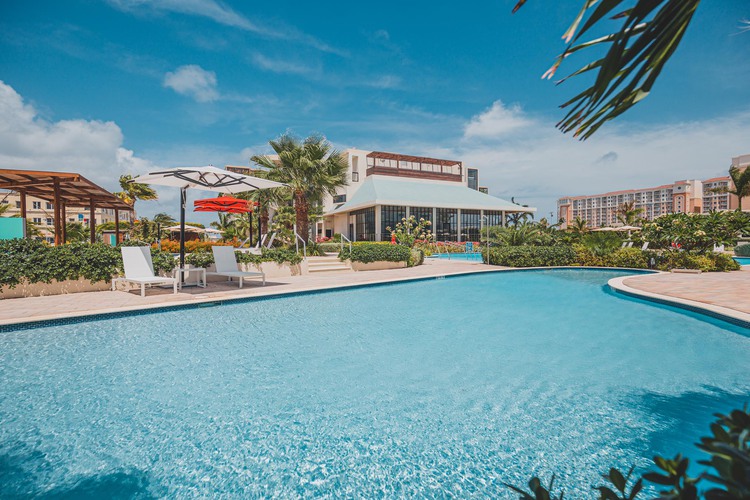 Large pool and seating are with buildings in the background