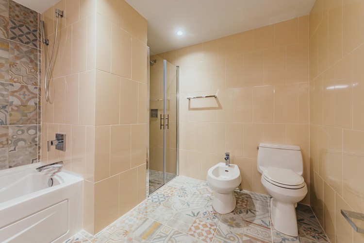 Toilet, bidet, shower, and tub with mosaic tiles on floor