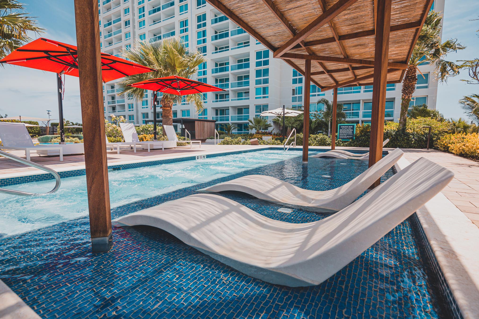 White chairs in pool beside lounge area with chairs and tables