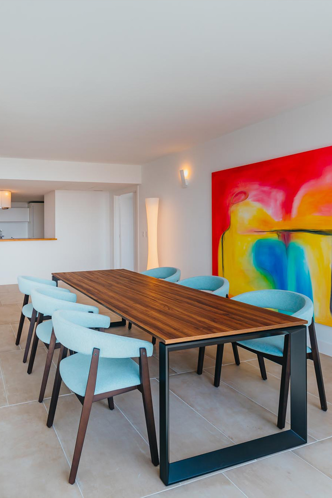 Brown table with blue chairs and colorful wall art