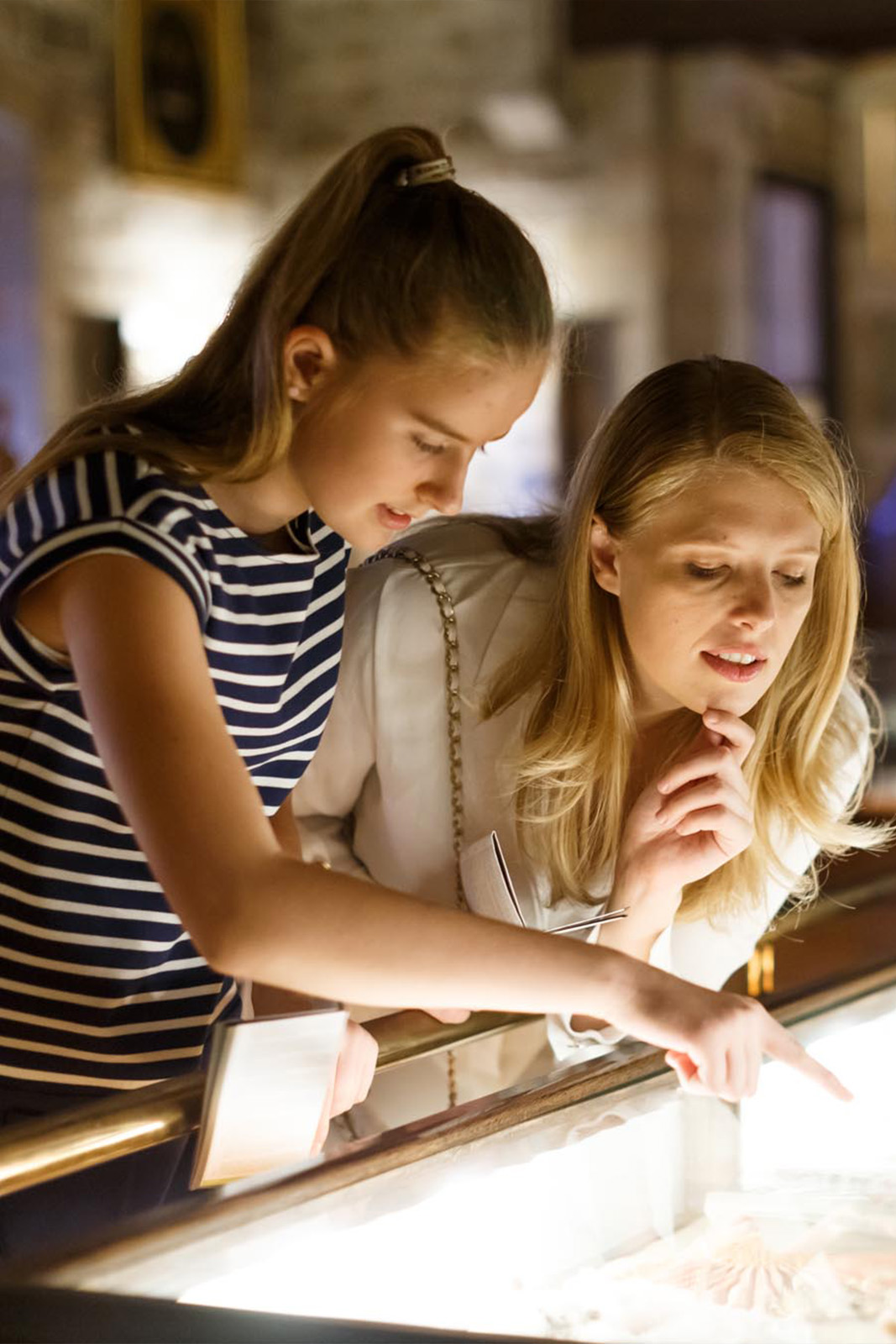 Two women pointing at glass case in museum