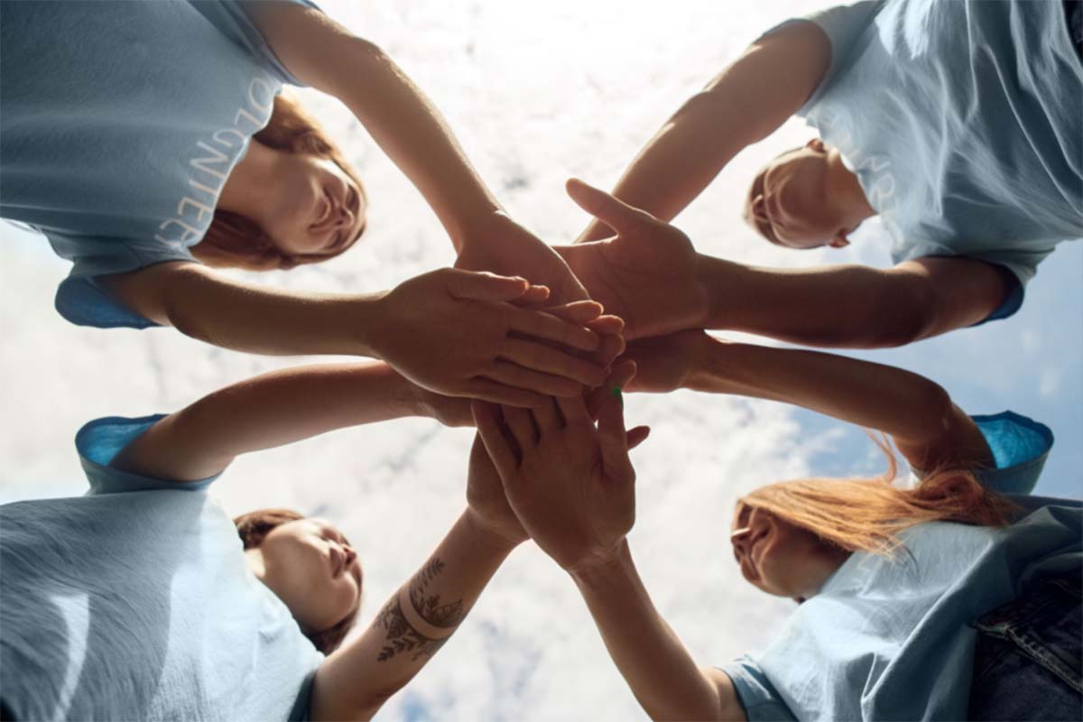Four youth stacking hands together